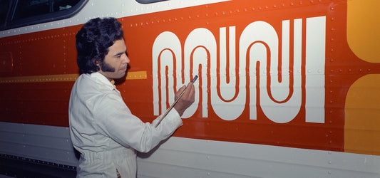 Walter Landor, creator of the Muni Worm logo is seen in this vintage photograph painting the Muni Worm logo on a transit vehicle.